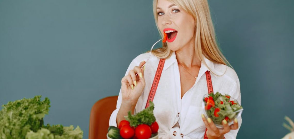 Woman enjoying a fresh salad with tomatoes and greens, promoting healthy eating.