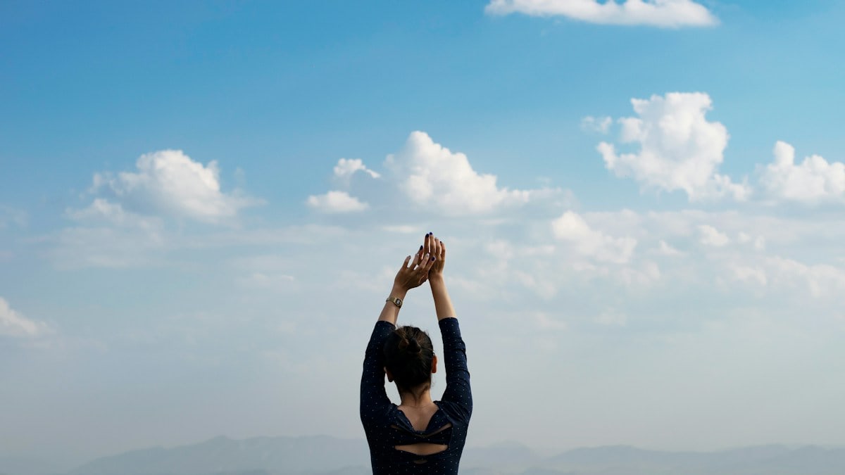 Woman raises hands towards the sky